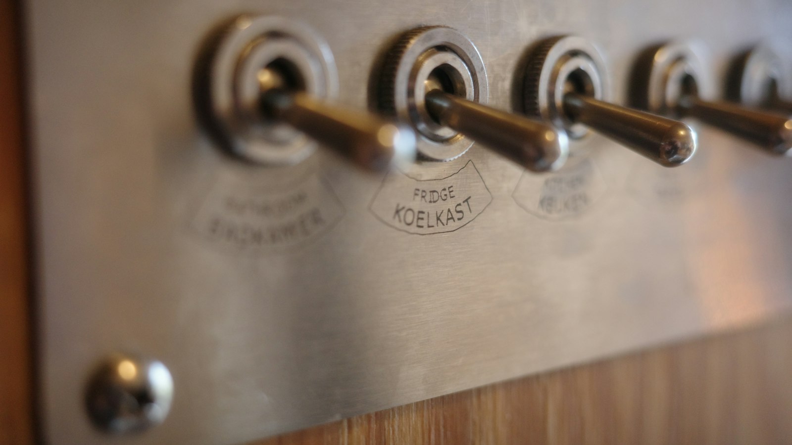 A row of metal toggle switches on a plain panel, each one wired to fire something else
