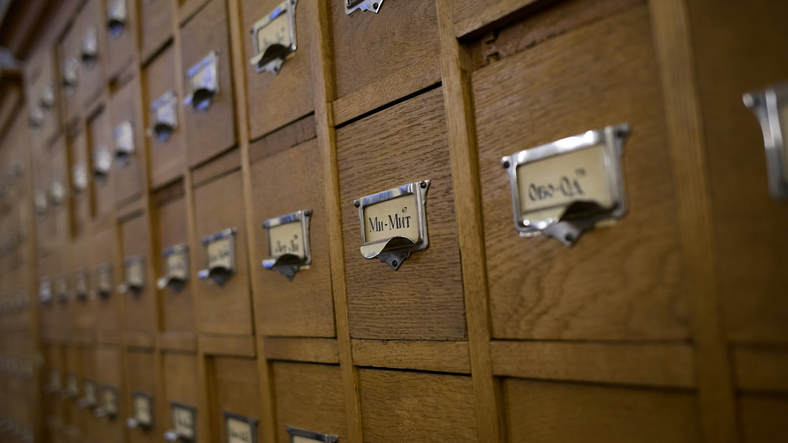 Rows of wooden library card catalog drawers with metal label holders