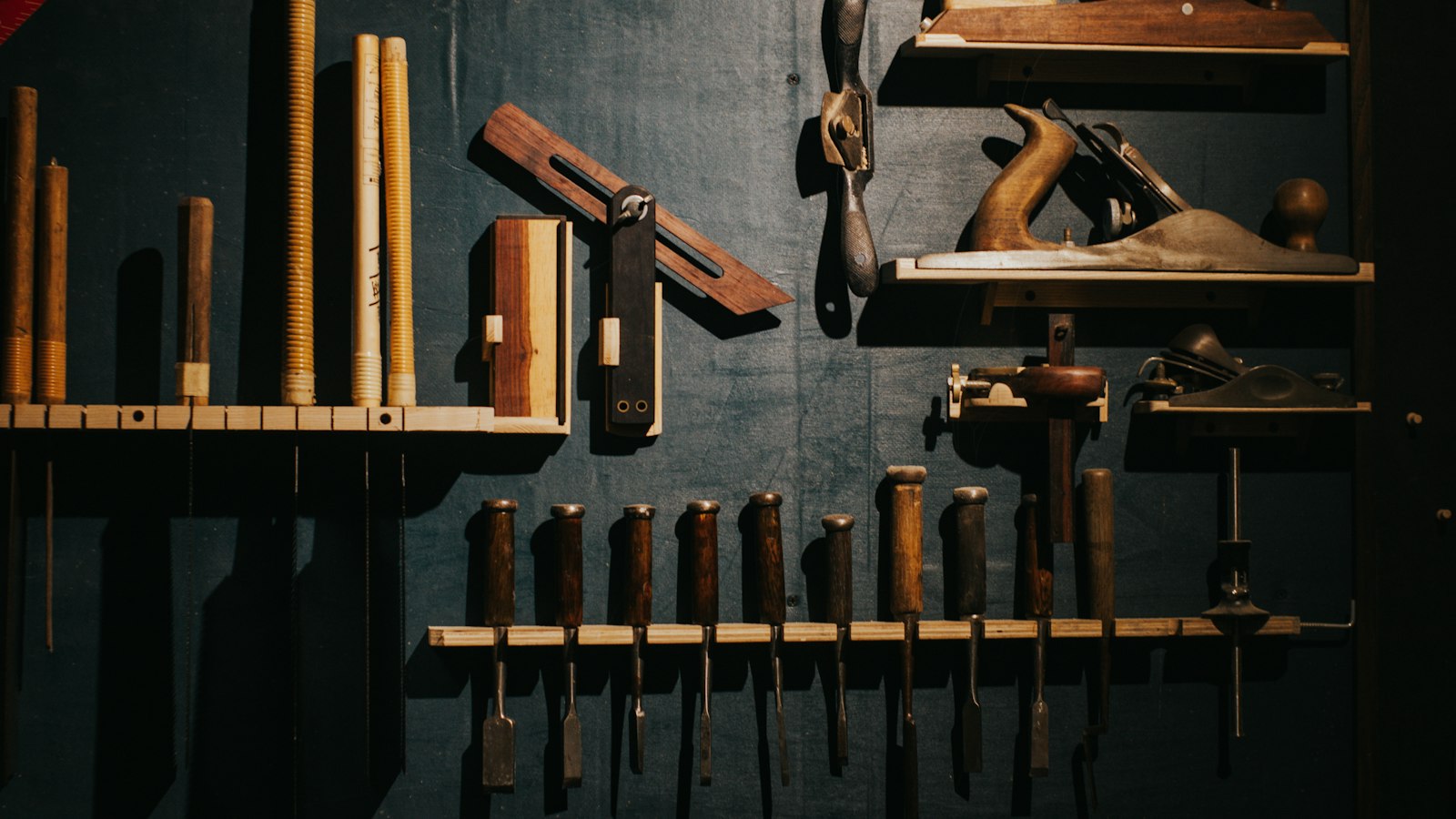 A wall of woodworking tools and chisels arranged in neat rows on a dark board