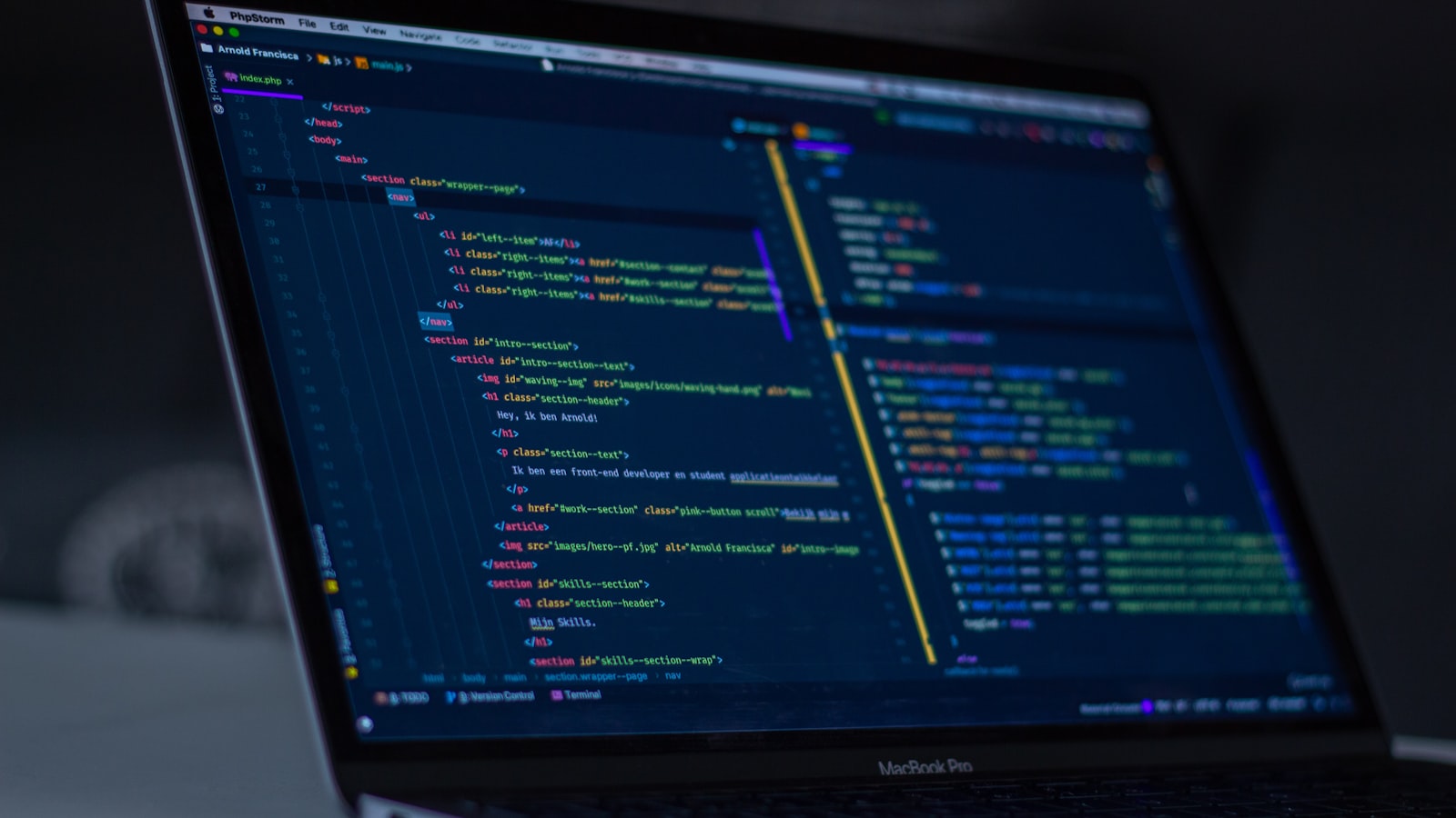 A laptop screen showing code in a dim room, deep navy tones, shot at an angle