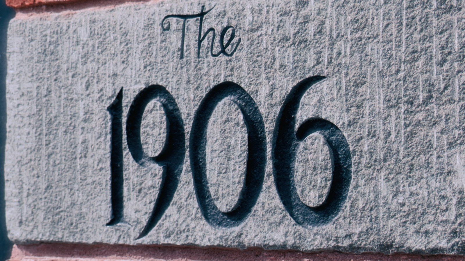 A carved stone nameplate set into a red brick wall, photographed close up